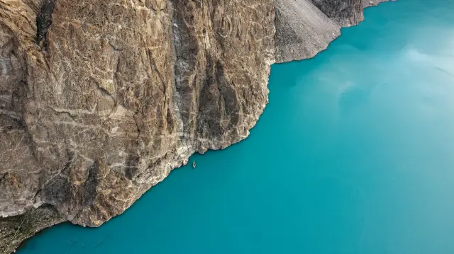 Turquoise Attabad Lake beside steep rocky slopes in Hunza.