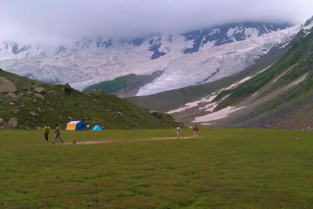 Tents on grassland below a glacier on the Rakaposhi base-camp trek.
